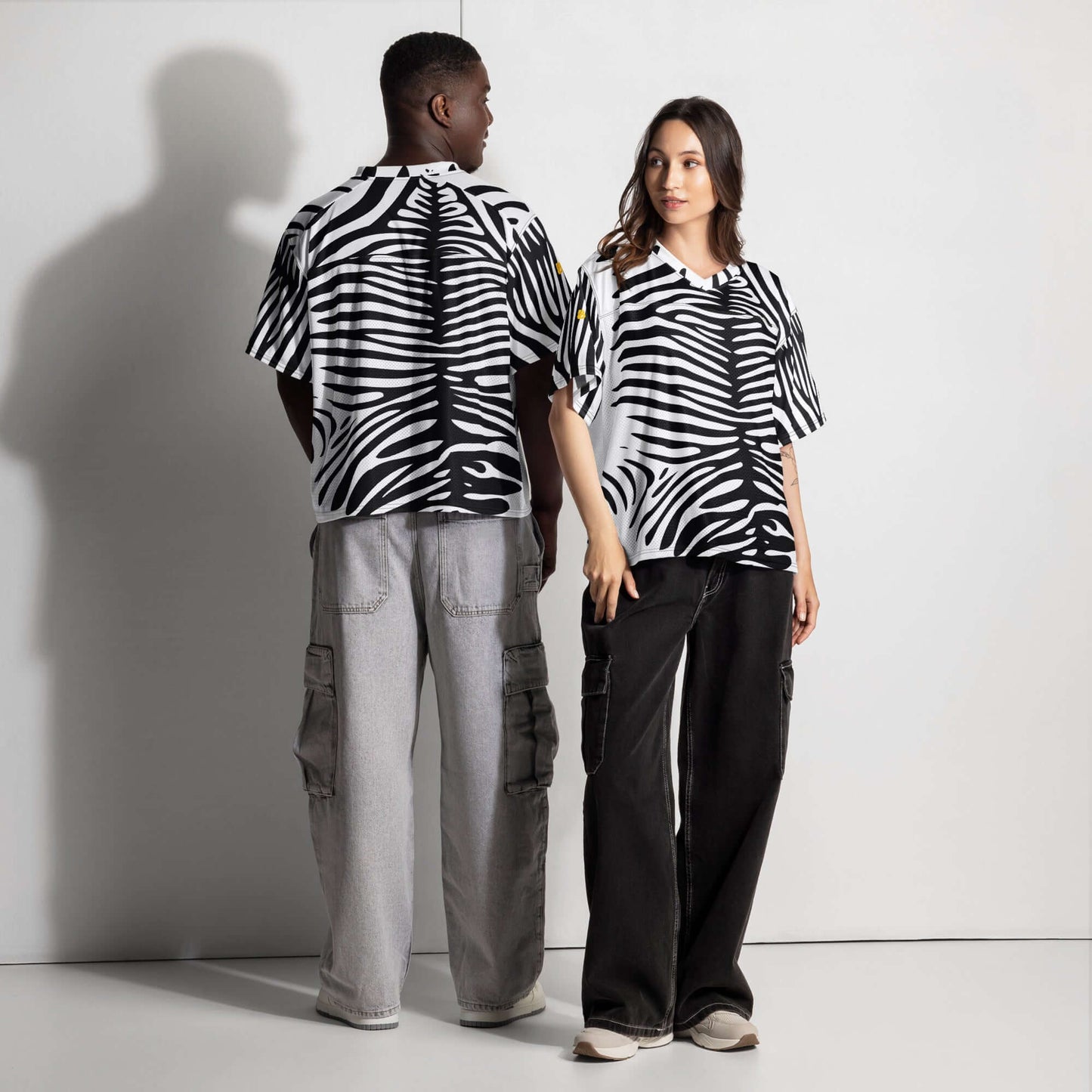 Models wearing black and white zebra patterned oversized tops with gray and black pants, showcasing relaxed urban fashion.
