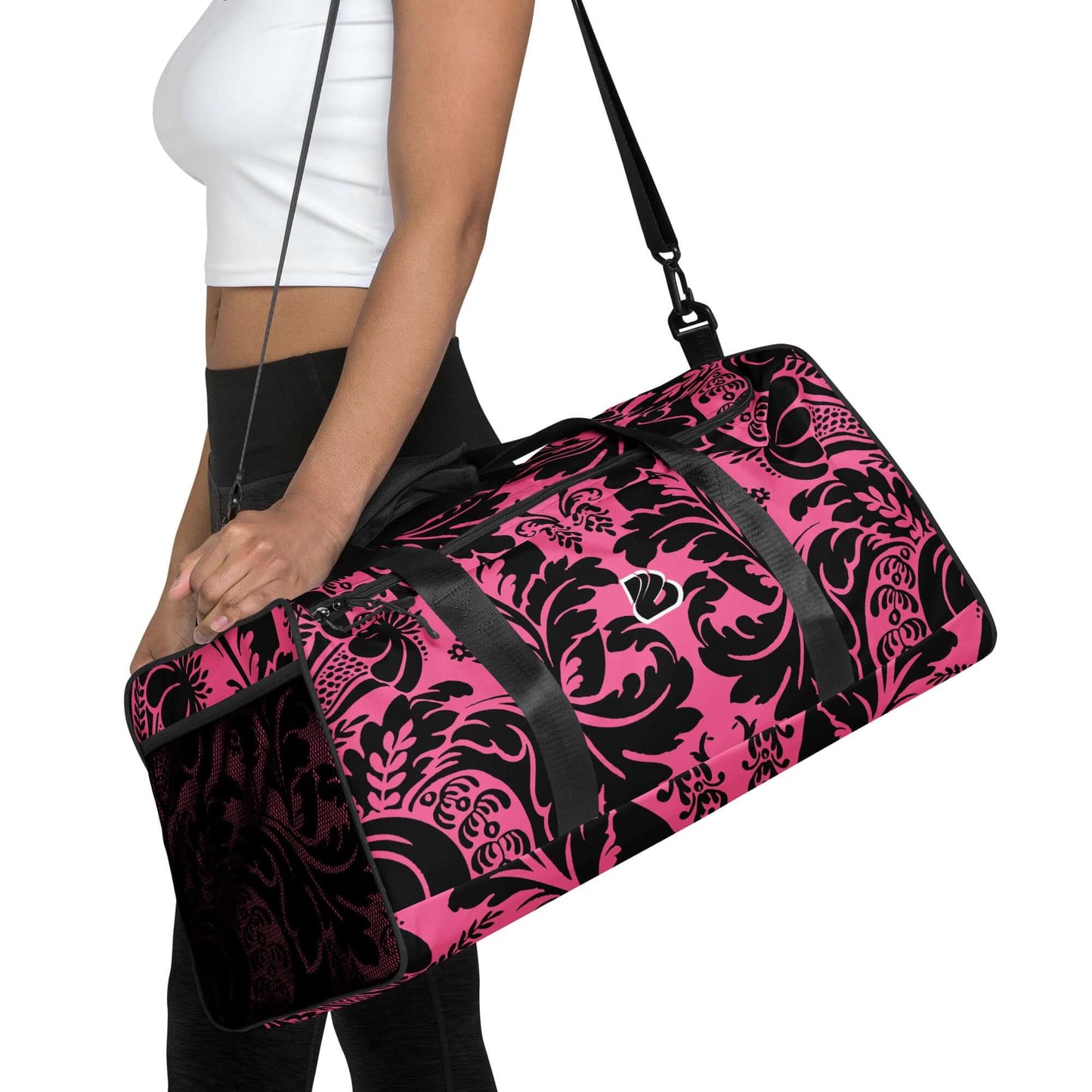 Woman carrying a stylish pink and black patterned Weekender N°29 travel bag with adjustable shoulder strap, ideal for gym and travel use.