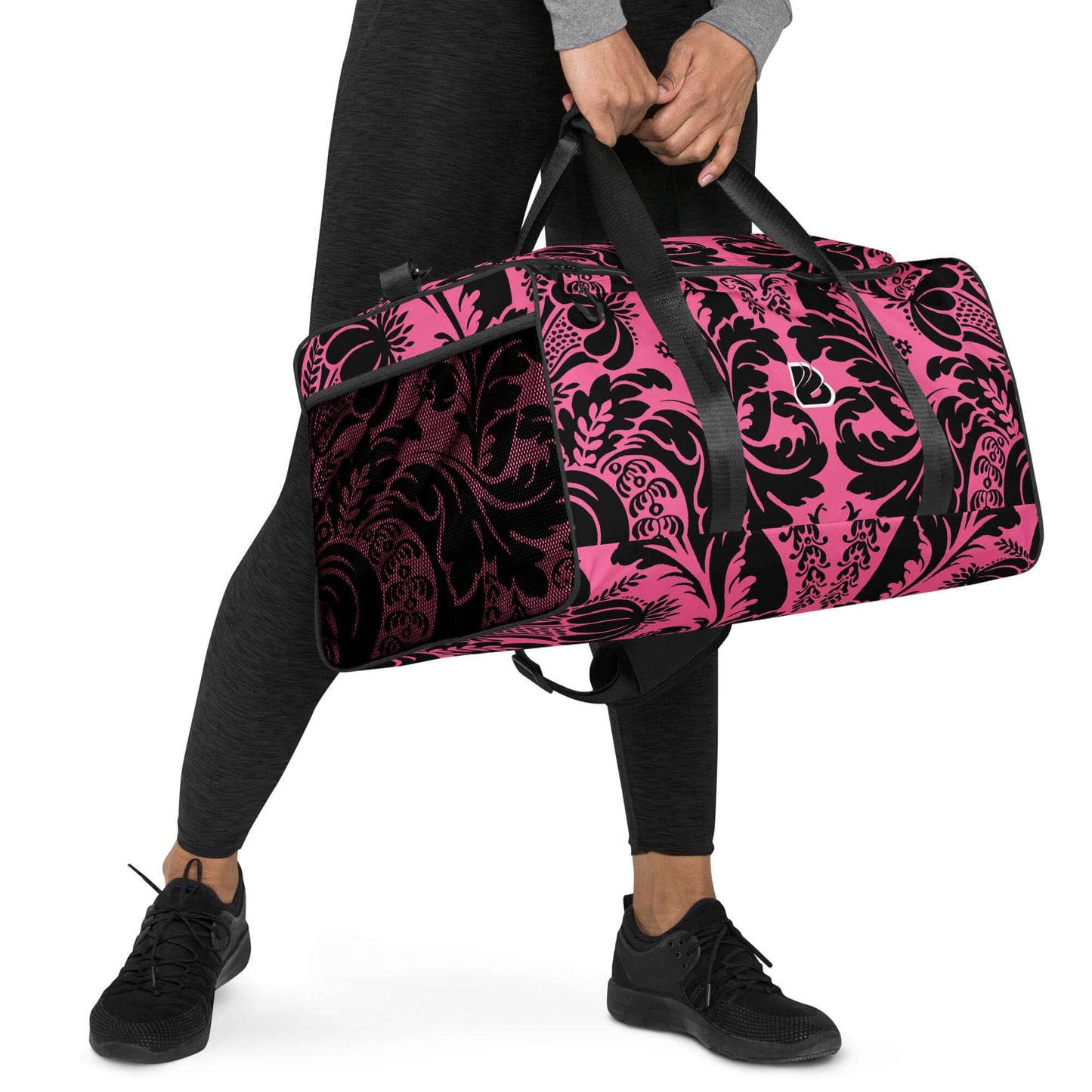 Person carrying Weekender N°29 bag in pink with black floral pattern, ideal for travel and gym use. Spacious with multiple compartments.
