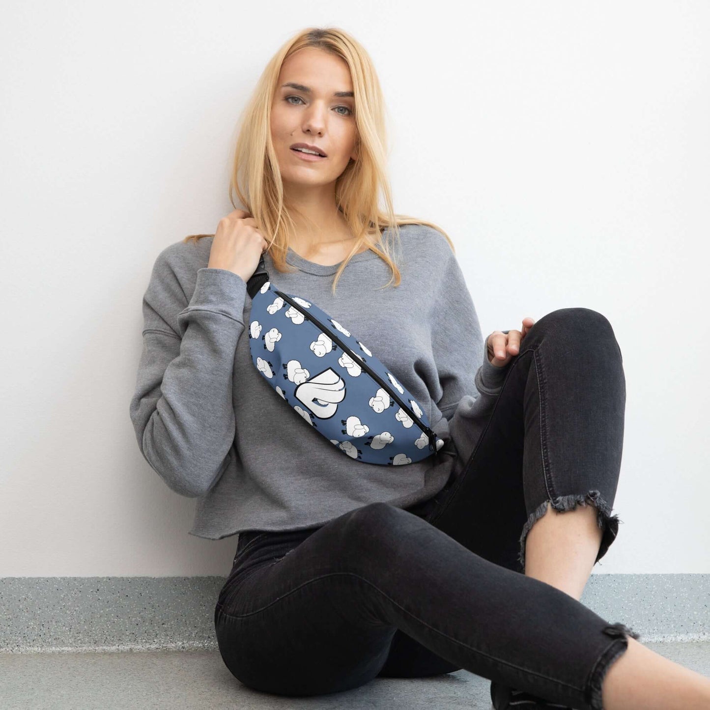 Woman sitting against wall wearing Gürteltasche N°32 with adjustable strap and inner pocket, ideal for travel and festivals.