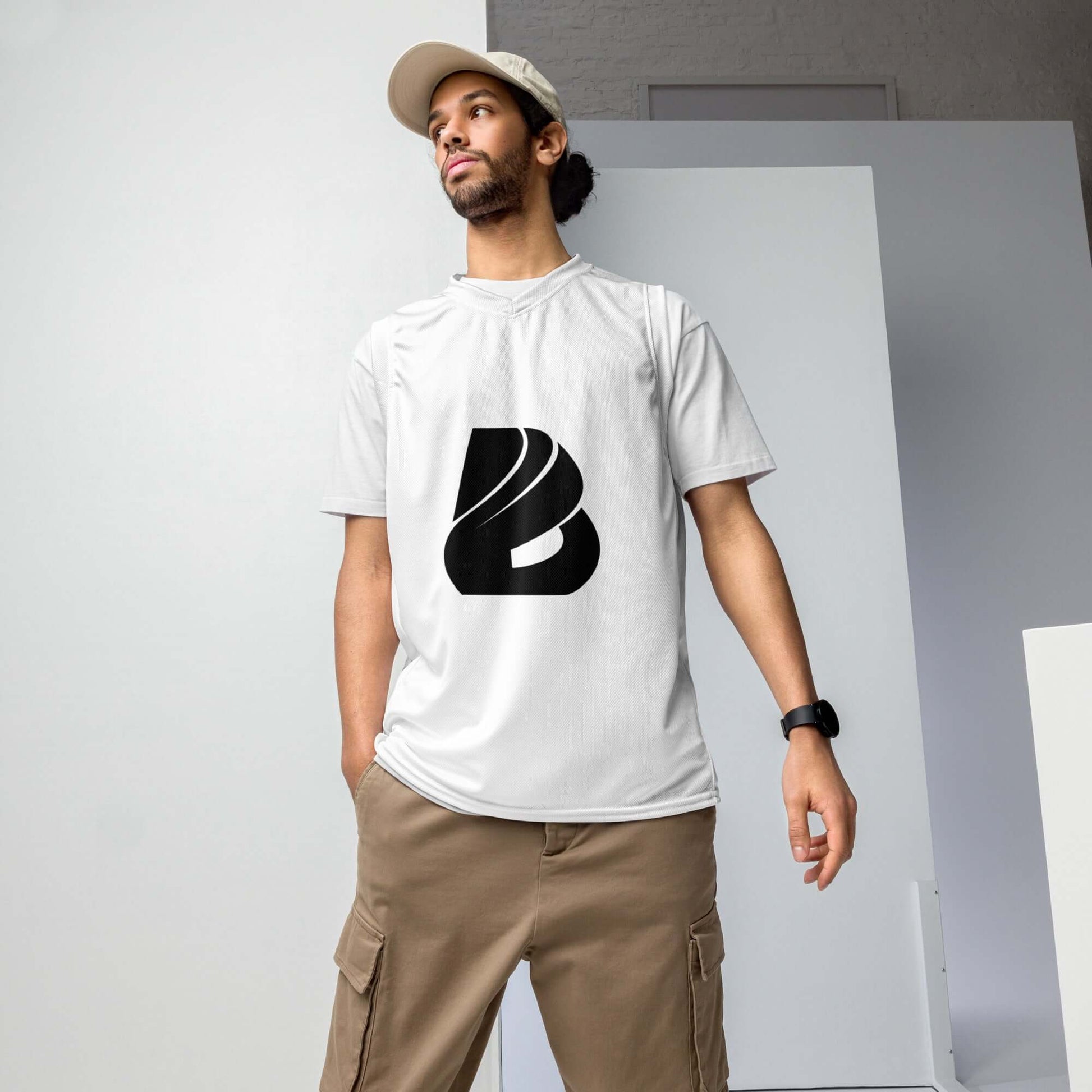 Person wearing white Recyceltes Unisex-Basketballtrikot N°0 with black logo, standing indoors, styled for both sports and streetwear.