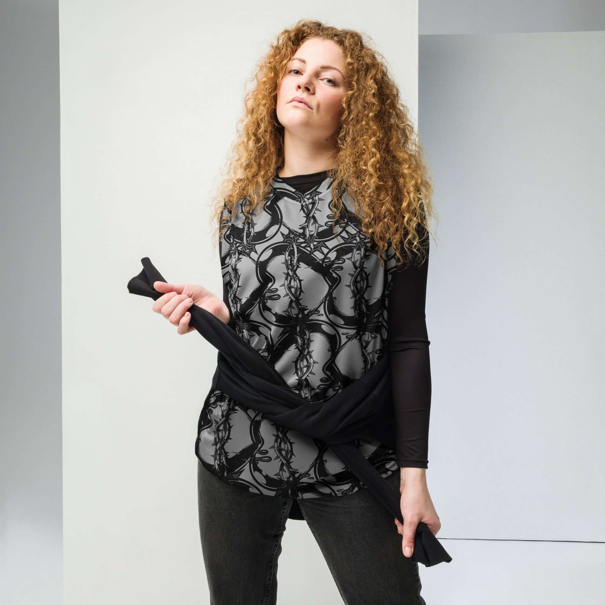 Person wearing Recyceltes Unisex-Basketballtrikot N°1, styled as streetwear with black patterned design, recycling symbol for sustainability