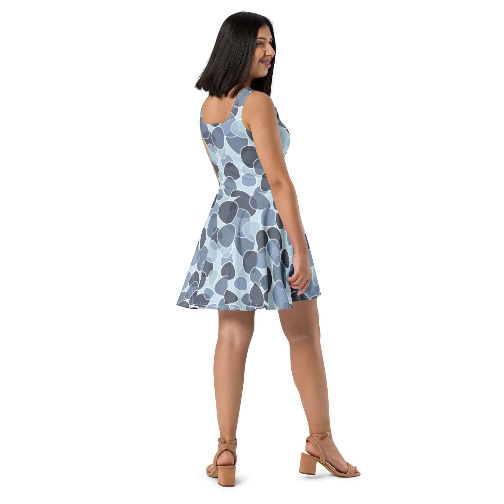 Woman wearing sleeveless Skater-Kleid N°9 with elegant flared skirt and blue polka dot pattern, shown from the side view.