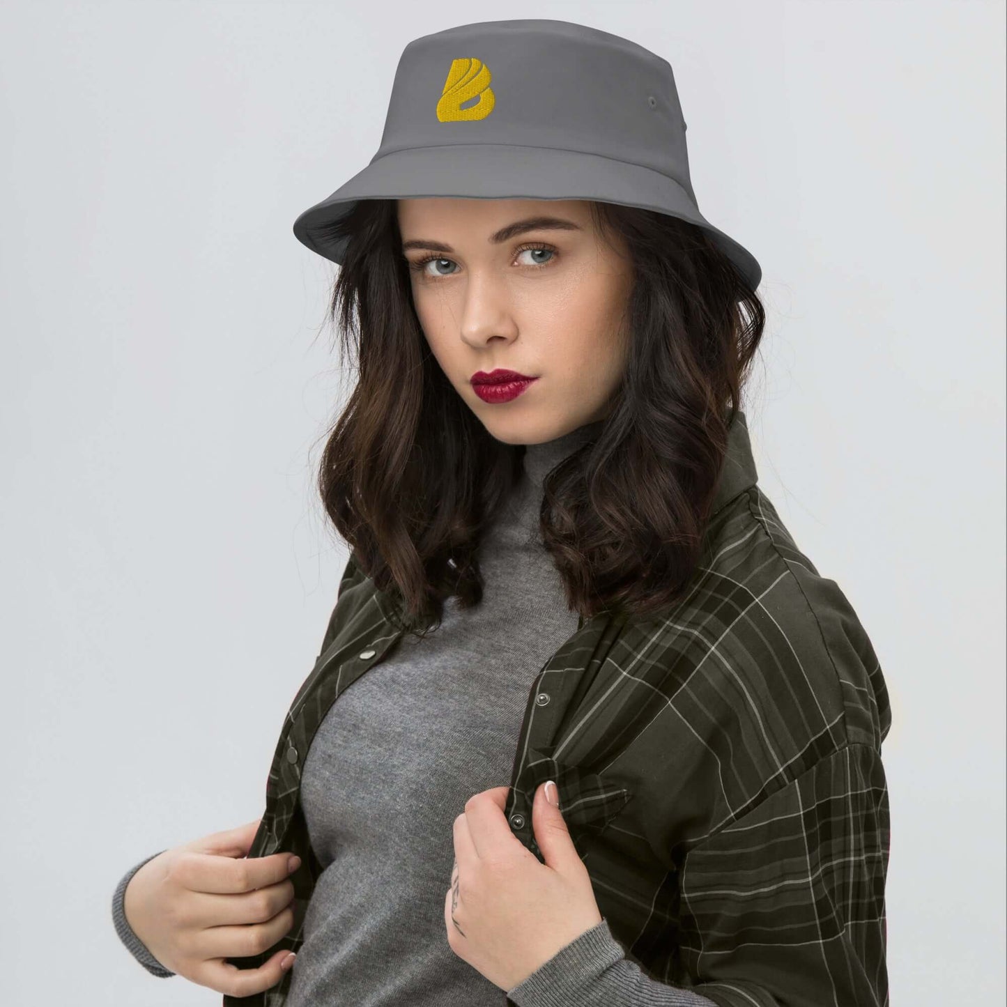 Young woman wearing Old School-Fischerhut N°2, showcasing vintage style and modern fit with gray hat and plaid shirt.