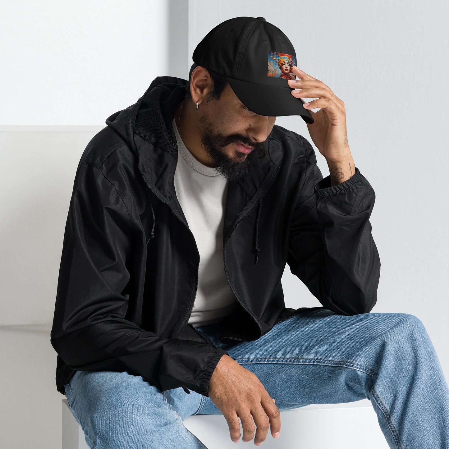 Man wearing Dad-Hat N°0 with black design and adjustable strap, demonstrating casual style, seated indoors.