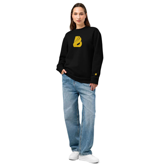 Woman modeling Urbaner Pullover in black with oversized fit and gold logo, paired with loose jeans and sneakers for a streetwear look.