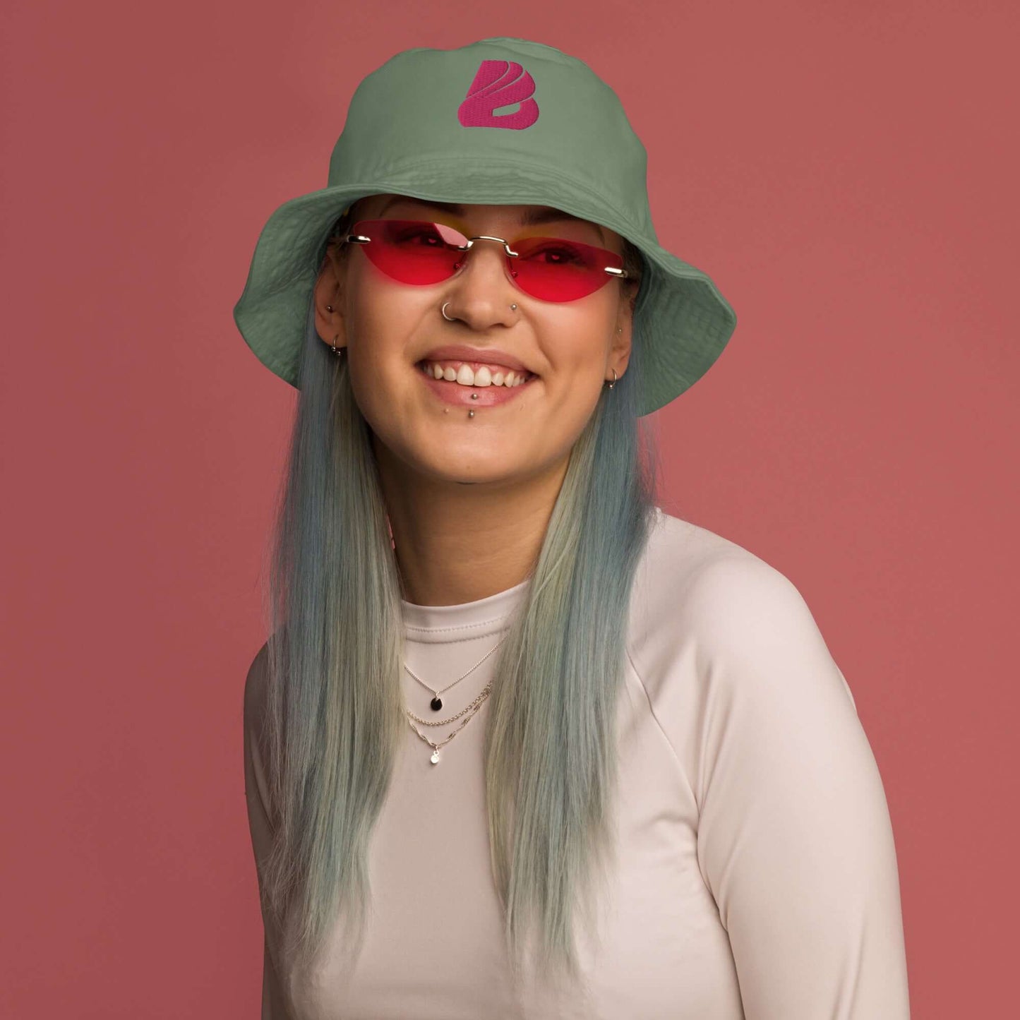 Person wearing Fischerhut aus Bio-Baumwoll-Twill N°1 with stylish glasses on a pink background