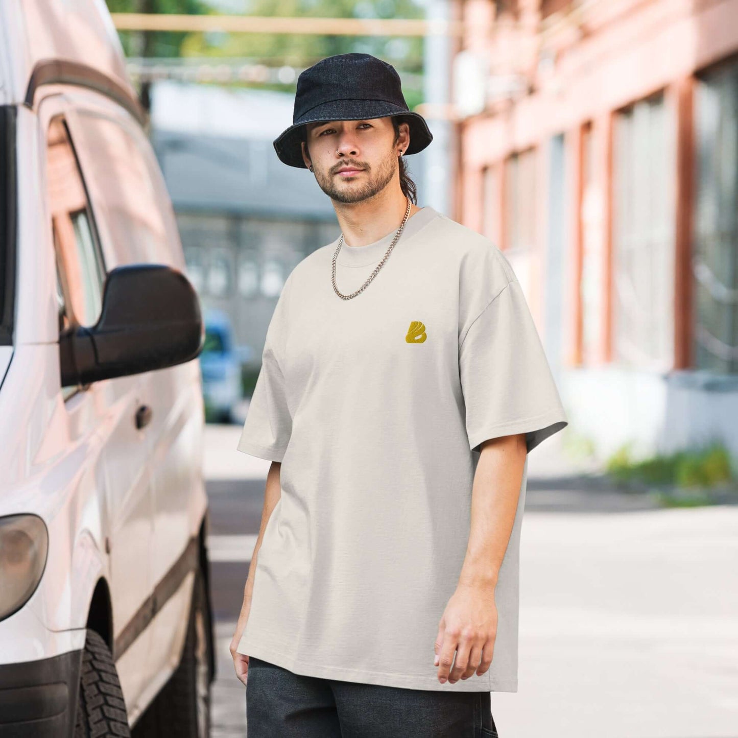 Stylish man wearing Oversized T-Shirt mit verwaschenem Look N°1 and hat, standing outdoors next to a van.