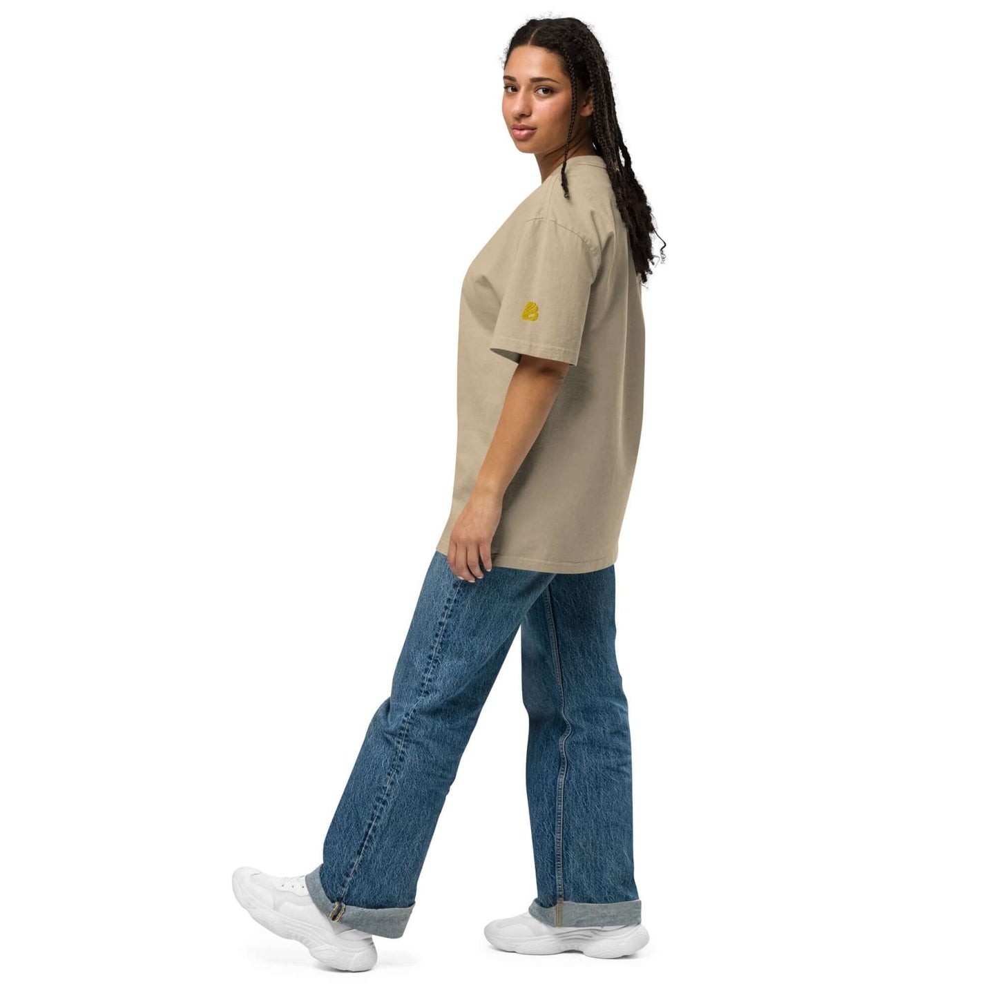 Person wearing an Oversized T-Shirt mit verwaschenem Look N°0, beige color, paired with blue jeans and white sneakers.