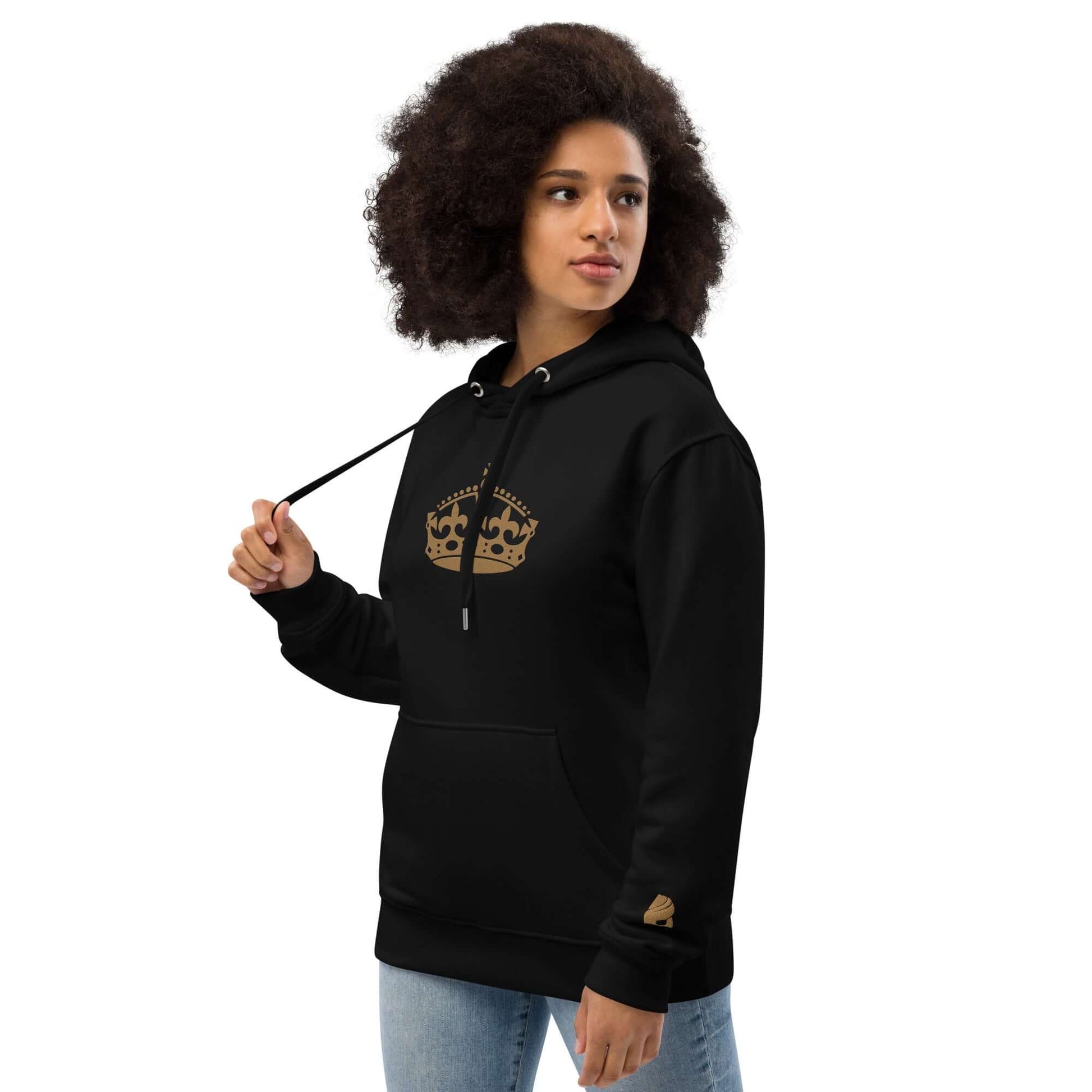 Woman wearing Hochwertiger Öko Kapuzenpullover N°10 in black with crown design, made from eco-friendly materials.