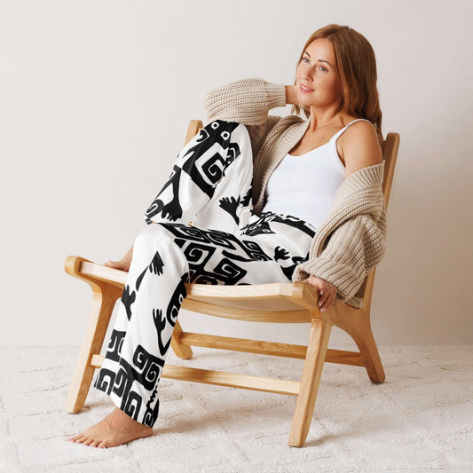 Frau trägt Pyjama-Hose für Damen aus seidigem Material, sitzt bequem in einem Stuhl. Loungewear für luxuriösen Komfort, entspannte Passform.