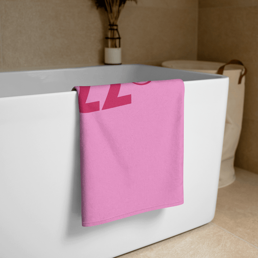 Pink Handtuch draped over white bathtub in modern bathroom setting