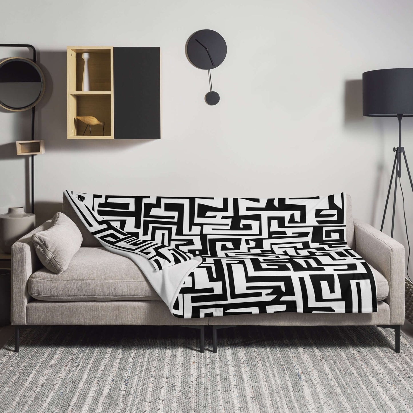 Tagesdecke N°4 with black and white geometric design draped over a modern gray sofa in a stylish living room.