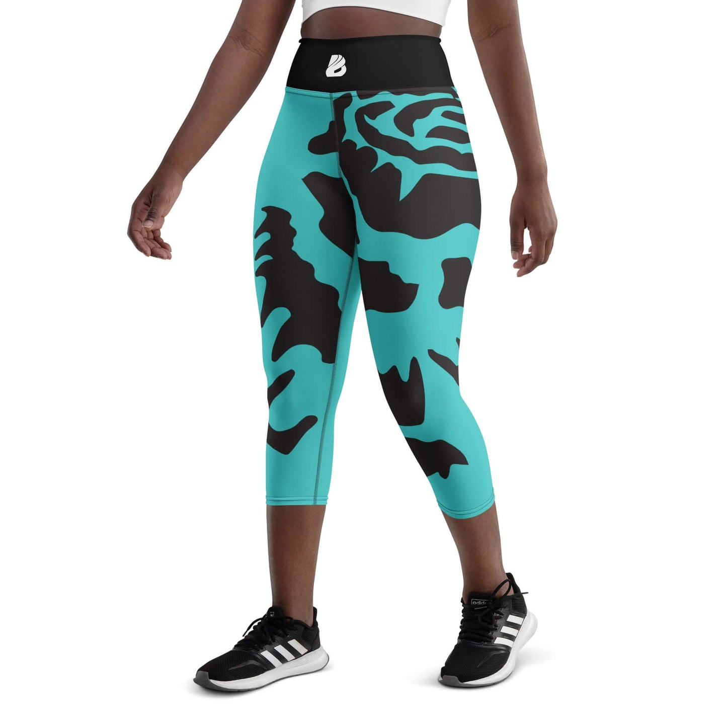 Woman wearing turquoise and black pattern Yoga-Capri-Leggings with high waistband for comfort in yoga or gym.