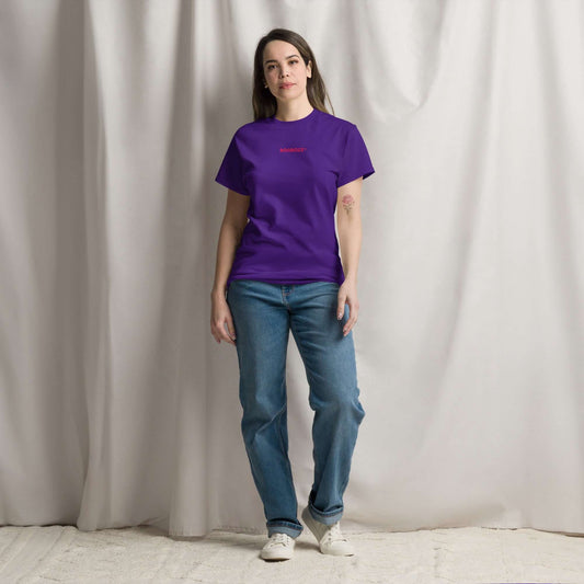 Woman wearing Klassisches Unisex T-Shirt N°0 in purple, 100% cotton, stylish streetwear outfit, standing against a gray backdrop.