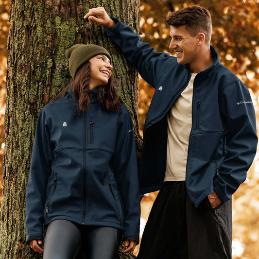 Couple wearing Weiche Columbia Softshell-Jacke N°1 in forest, highlighting wind and water resistance, venturing on outdoor adventures.