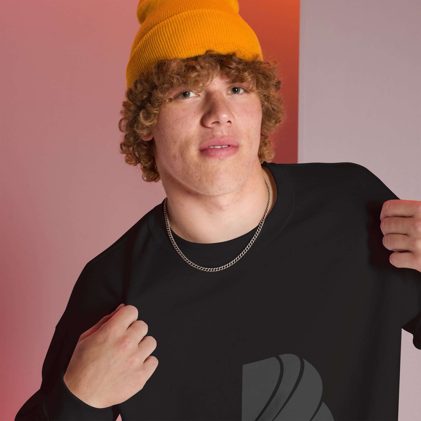 Young person wearing a black Unisex-Pullover and a yellow beanie against a colorful background.