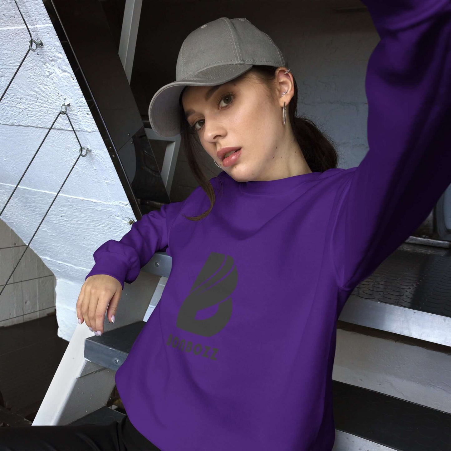 Woman wearing a purple Unisex-Pullover, sitting on stairs, showcasing a comfortable and stylish sweatshirt.