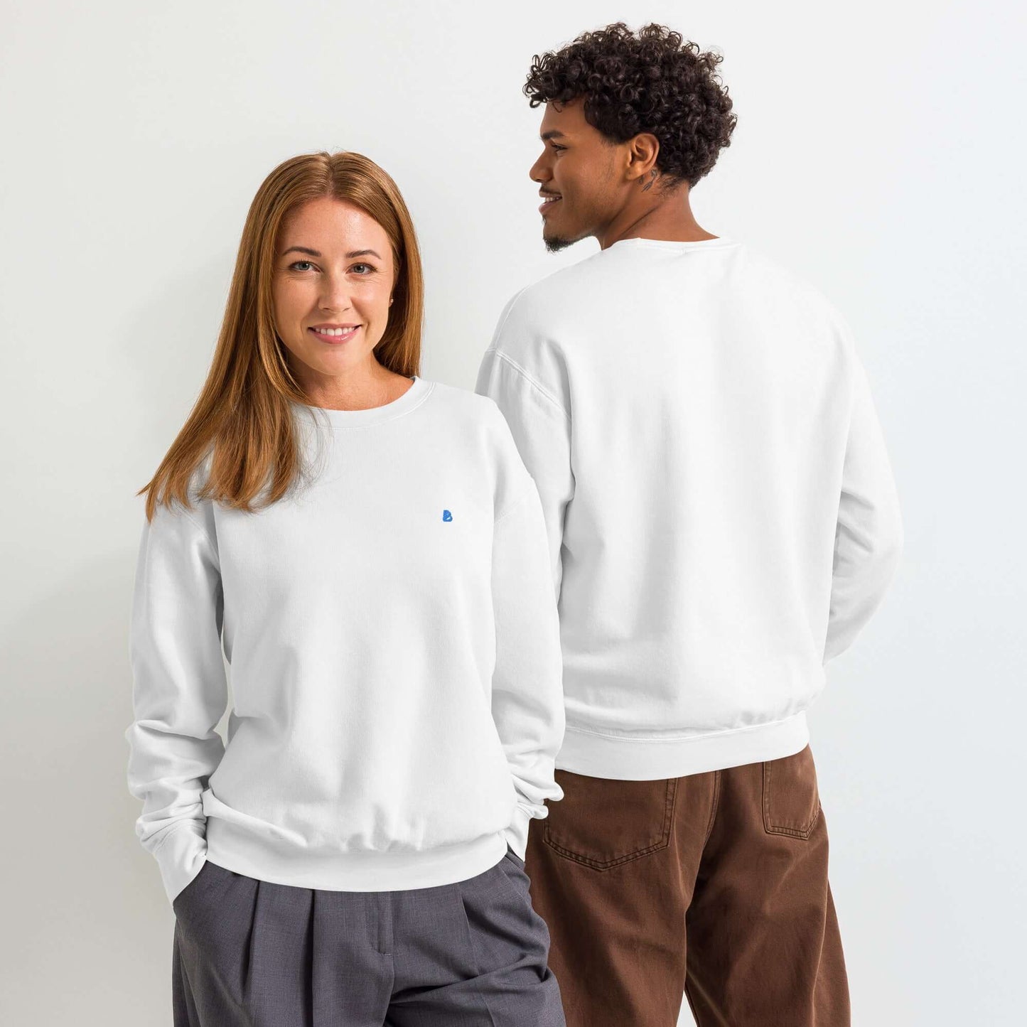 Zwei Personen tragen einen leichten textilgefärbten Unisex-Fleece-Pullover mit Rundhalsausschnitt in einem weißen Raum.