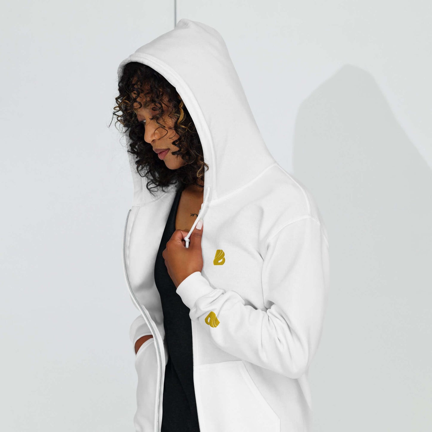 Woman wearing Unisex Heavy-Blend Zip Hoodie N°0 in white with hood up, featuring a front zipper and comfortable pockets.