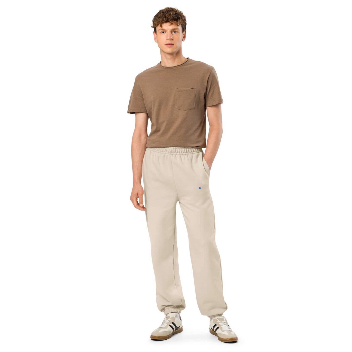 Person wearing Schwere Jogginghose in beige with elastic cuffs and deep side pockets, styled in 90s fashion.