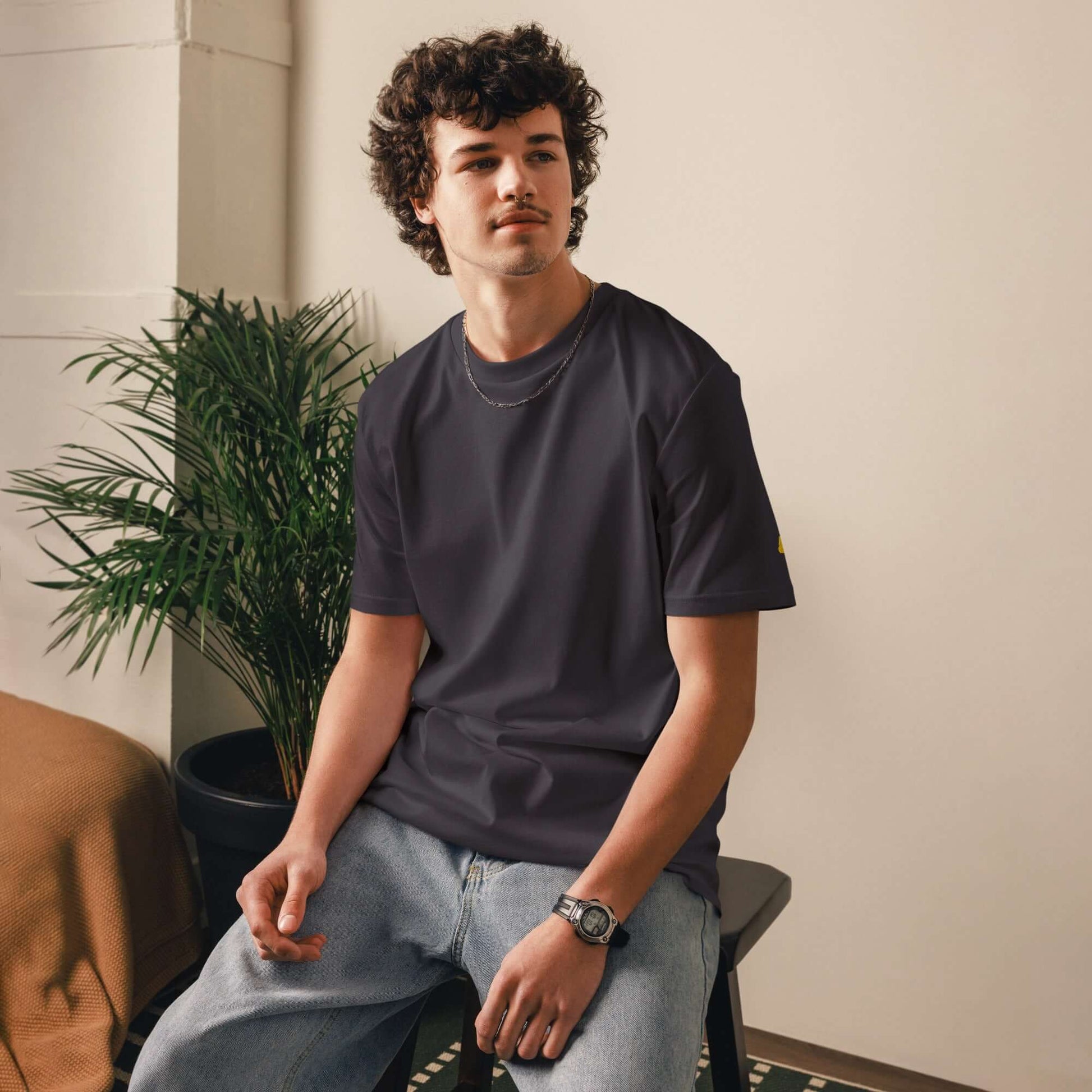 Model wears Unisex-Bio-Baumwoll-T-Shirt in living room setting.