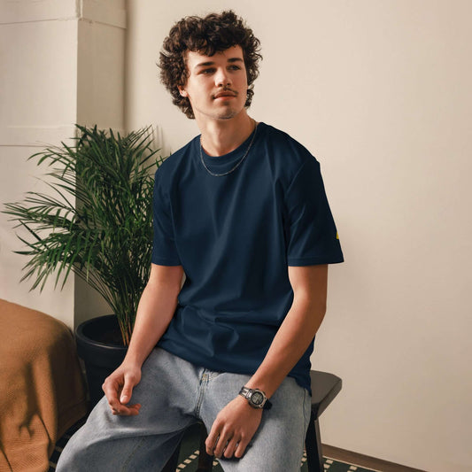 Person wearing Unisex-Bio-Baumwoll-T-Shirt in dark color, sitting in a modern room, showcasing eco-friendly fashion.