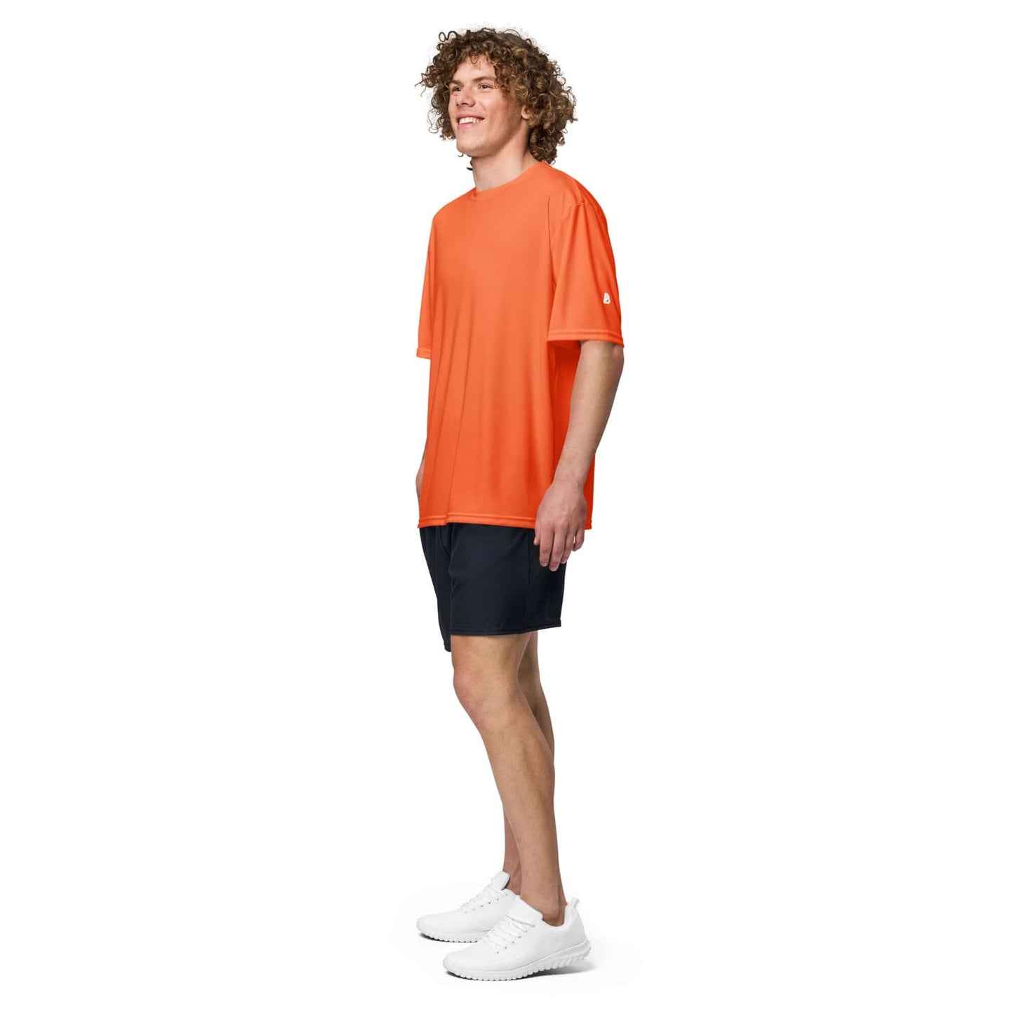 Model wearing Unisex Performance T-Shirt mit Rundhalsausschnitt N°0 in orange, paired with black shorts, showcasing activewear style.