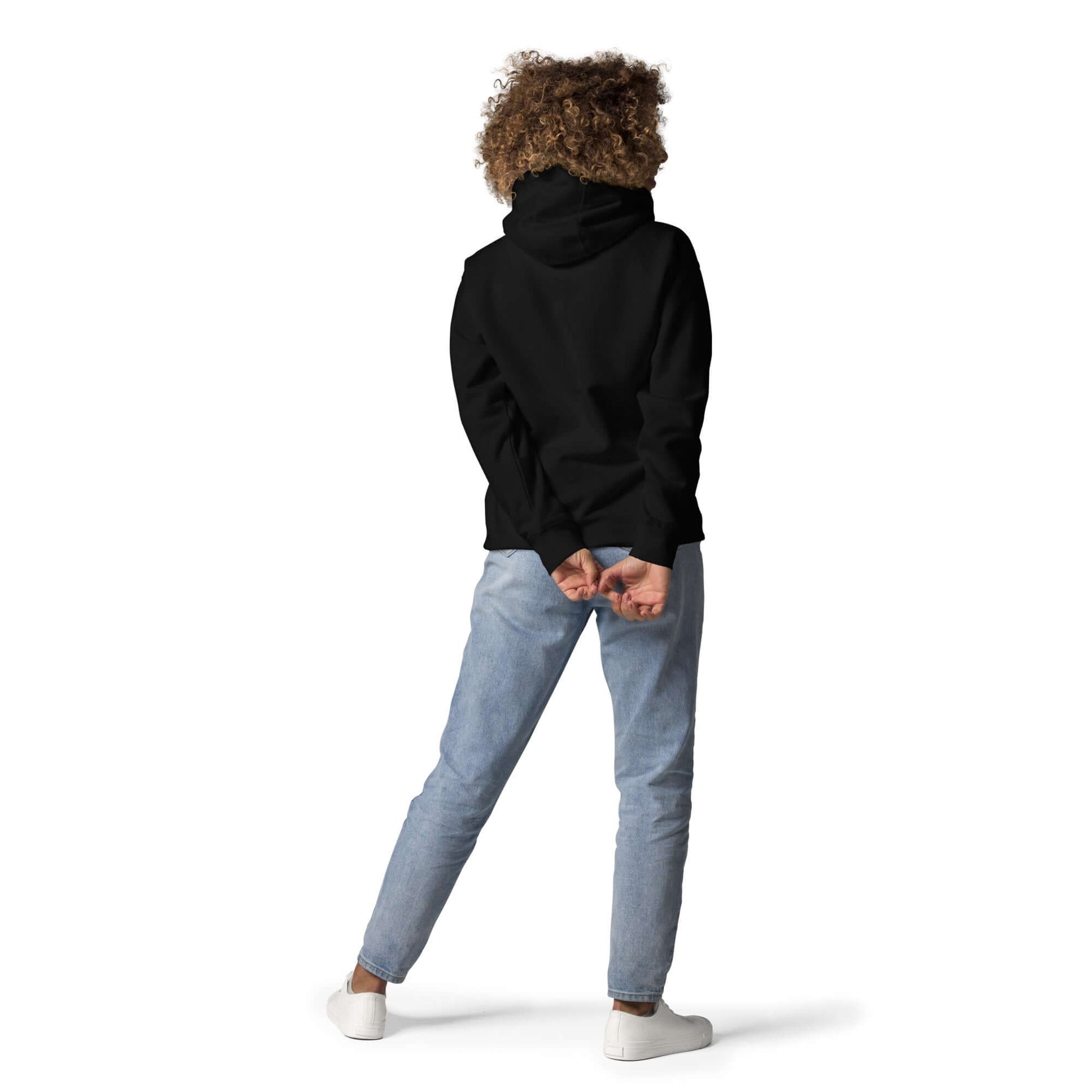 Person wearing Unisex-Kapuzenpullover N°48 in black with hood up, showcasing streetwear style from the back, paired with jeans and sneakers.