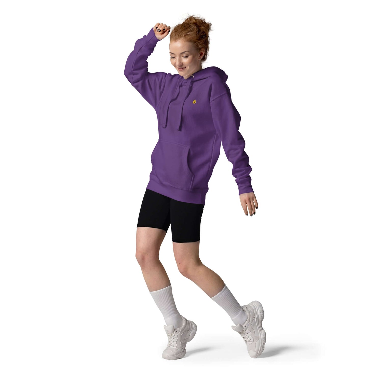 Model trägt Unisex-Kapuzenpullover N°50 in Lila, kombiniert mit schwarzen Shorts und weißen Socken, im Bewegungsmodus.
