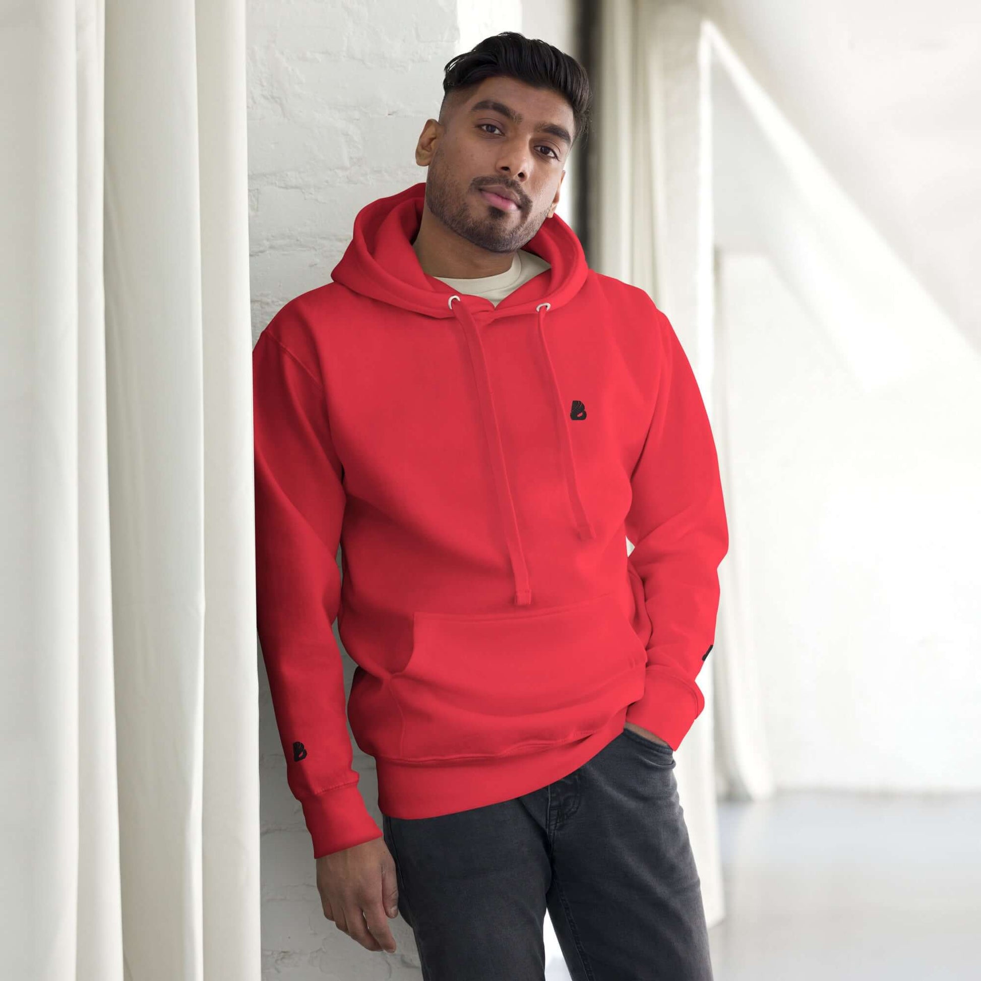 Person wearing Unisex-Kapuzenpullover N°49 in red with a cozy design and front pouch, perfect for cool evenings.