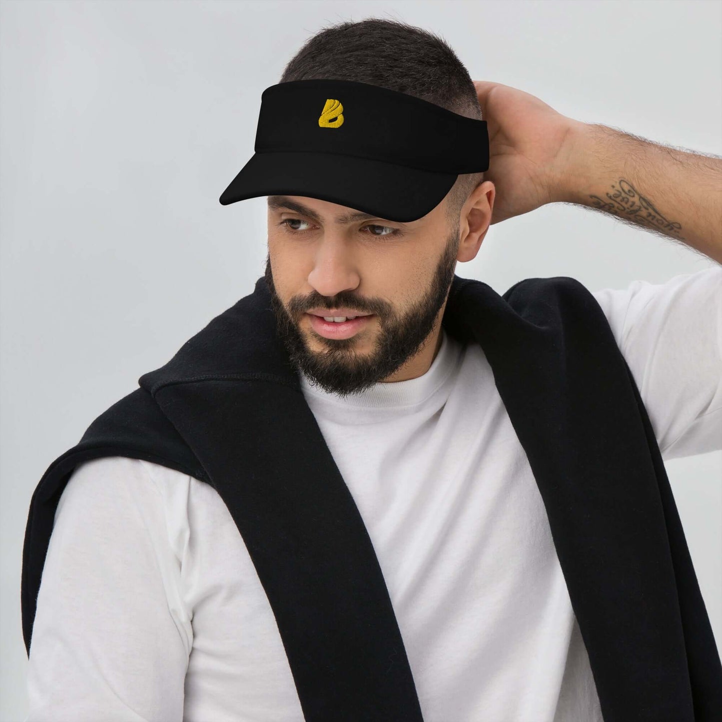 Man wearing Visor N°1, black embroidered hat with moisture-wicking fabric, protecting eyes from sun. Ideal for outdoor activities.