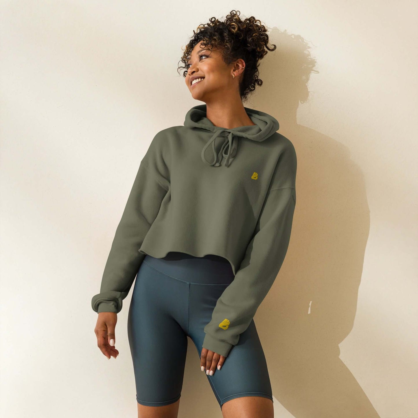 Woman wearing trendy Crop-Hoodie N°1 with open hem and drawstrings, paired with cycling shorts. Made of cotton-polyester blend.