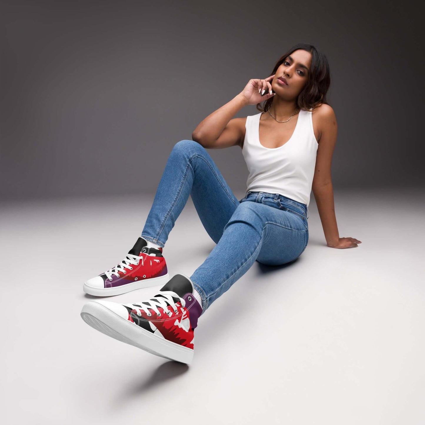 Damen in weiße Tanktop und Jeans mit roten High-Top Leinenschuhen in einem modernen, stylischen Setting.