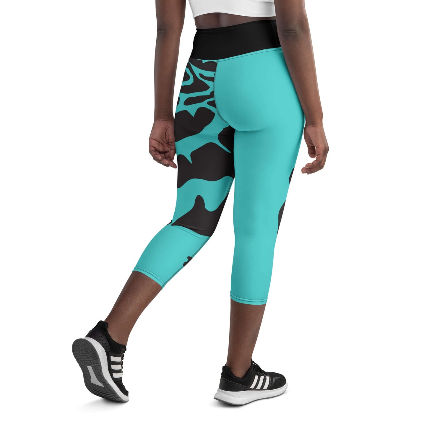 Hinteransicht einer Frau in türkisfarbenen Yoga-Capri-Leggings mit hohem Bund und schwarzem Muster.