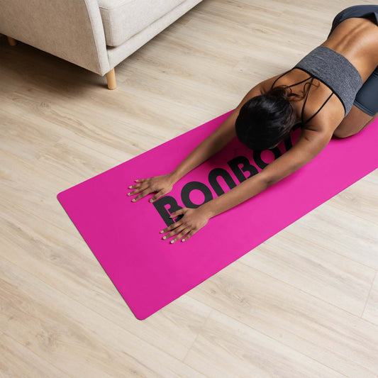 Woman practicing child pose on pink Yoga-Matte N°1 with non-slip rubber bottom and microsuede top, indoors on wood floor.