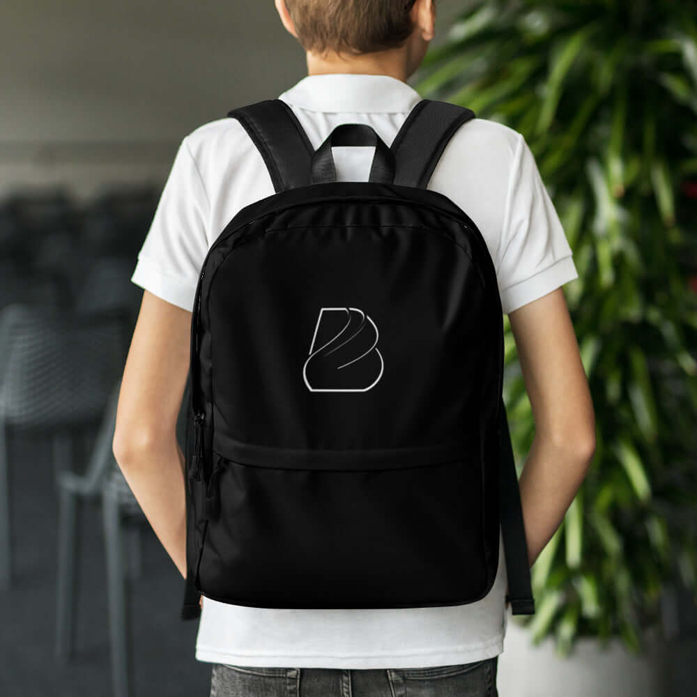 Teenager carrying Rucksack N°2 in black, perfect for daily use and sports, with water-resistant material and laptop compartment.