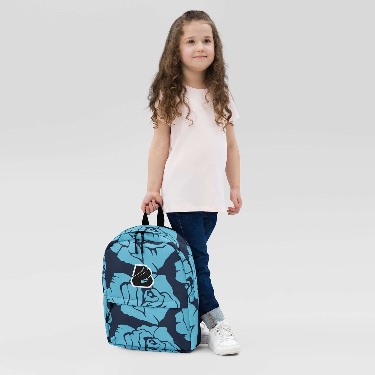Young girl holding Rucksack N°4 in blue floral design, ideal for daily use and sports, featuring laptop pocket and water-resistant material.