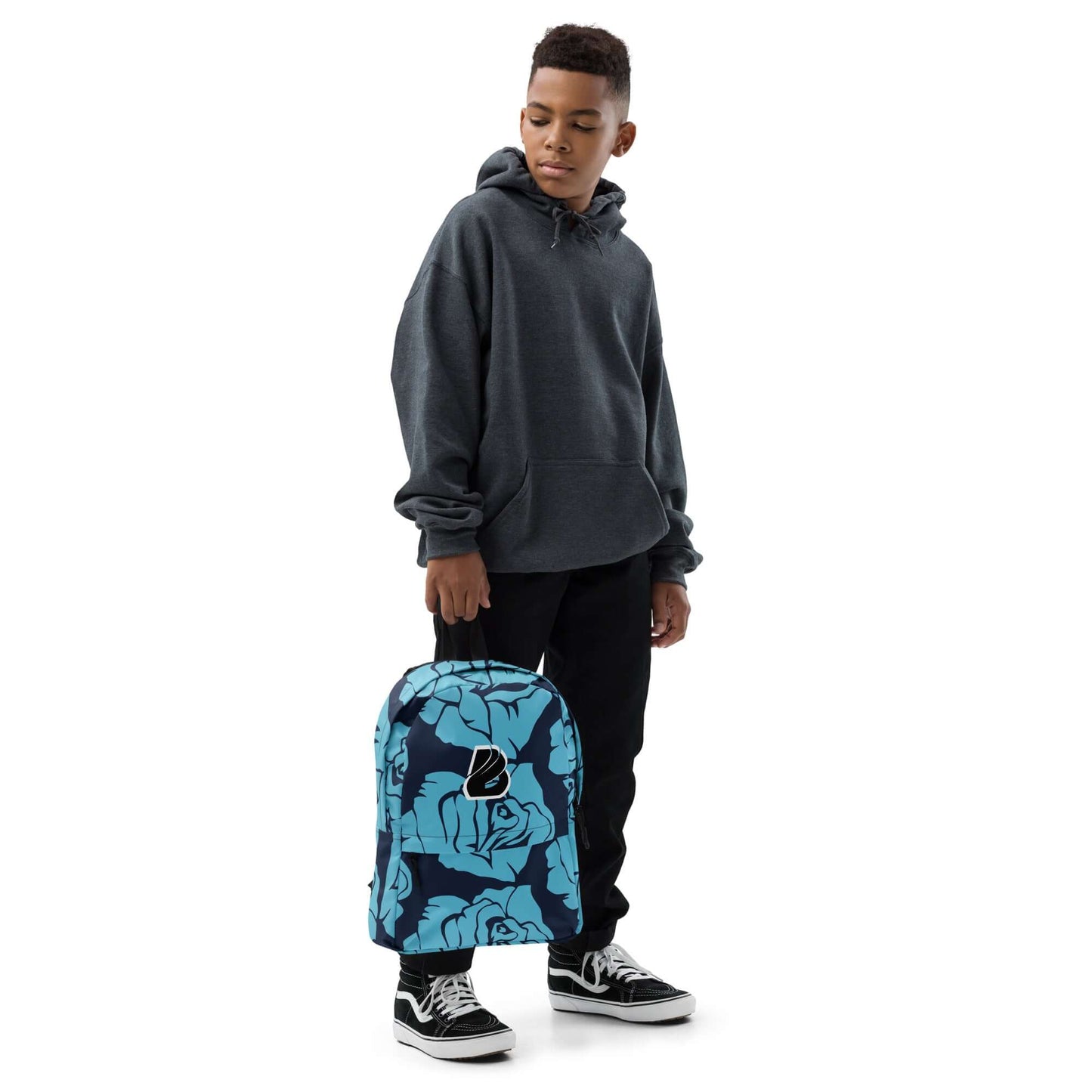 Teen holding blue floral Rucksack N°4, wearing dark hoodie and sneakers.