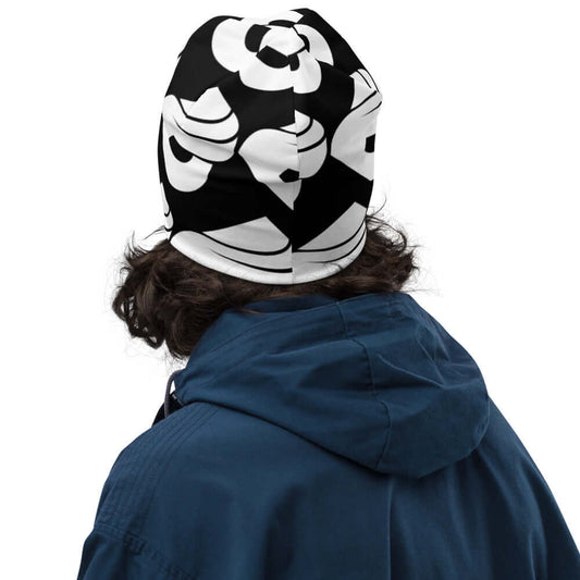 Warm and stylish Allover-Beanie N°0 with black and white pattern, perfect for cold days, shown on a person with curly hair and blue jacket.