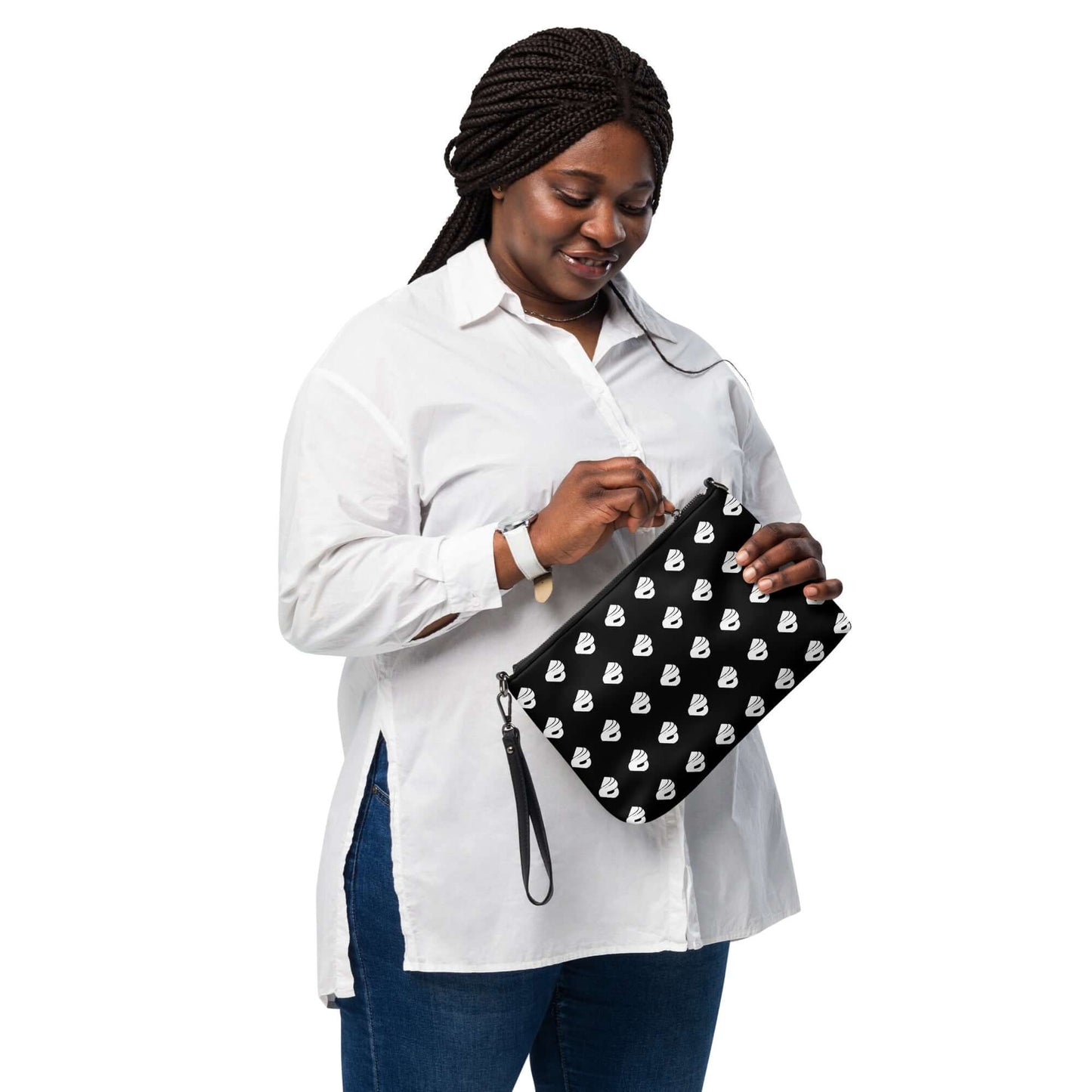 Woman holding a stylish black and white wristlet bag with heart pattern, wearing a white shirt and jeans.