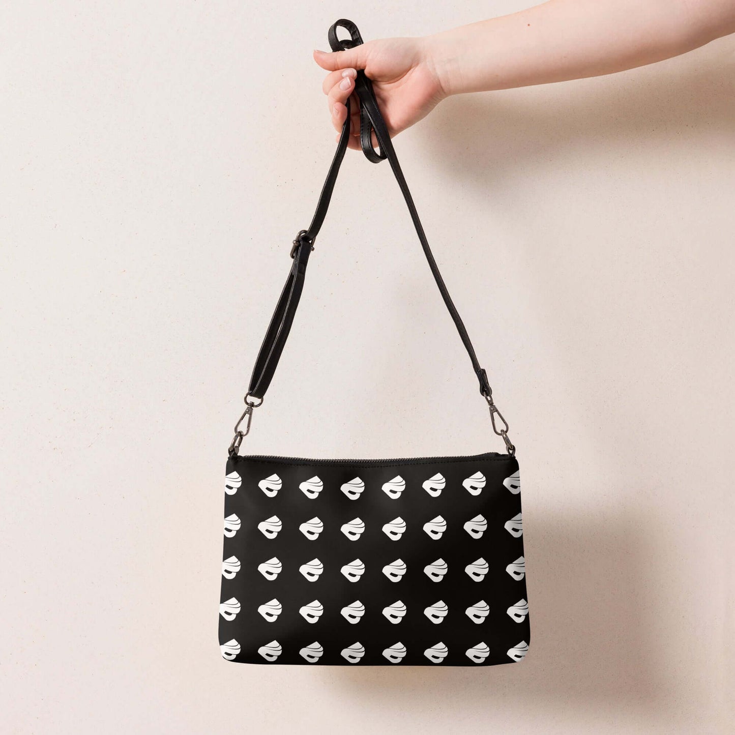 Hand holding Umhängetasche N°0 with black pattern, detachable strap, and dark grey accents made from premium faux leather.