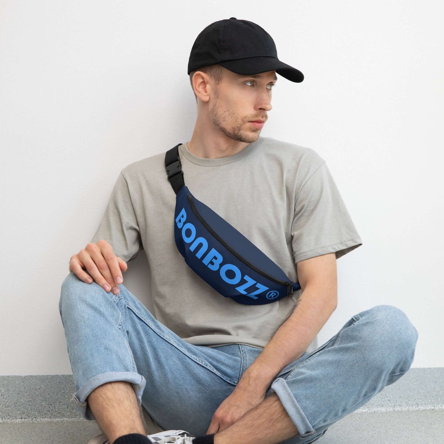 Mann sitzt an Wand mit stilvoller Gürteltasche N°26, perfekt für Reisen und Festivals, mit verstellbarem Riemen und Innentasche.