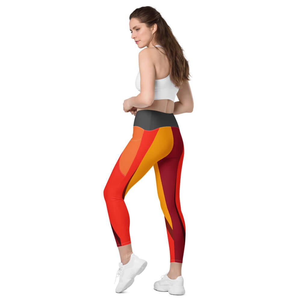 Model wearing high-waisted Leggings mit Taschen N°0 with vibrant red and orange design, highlighting side pockets and four-way stretch fabric.