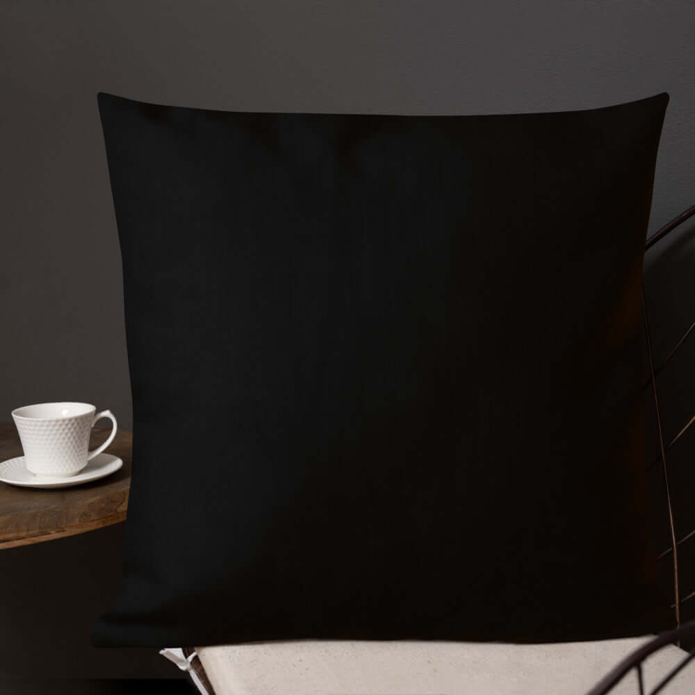 Premium-Kissen N°0 in elegantem Schwarz auf Sessel, mit verstecktem Reißverschluss und leichtem Leinengefühl, neben Teetasse.
