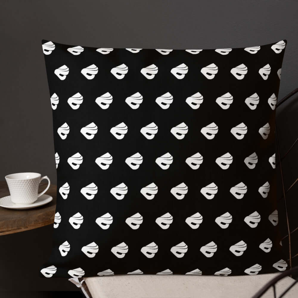 Premium-Kissen N°0 with black and white pattern on a chair beside a coffee cup