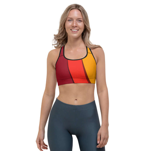 Woman wearing Sport-BH N°3 in red and yellow, featuring moisture-wicking fabric and supportive shoulder straps for medium intensity training.