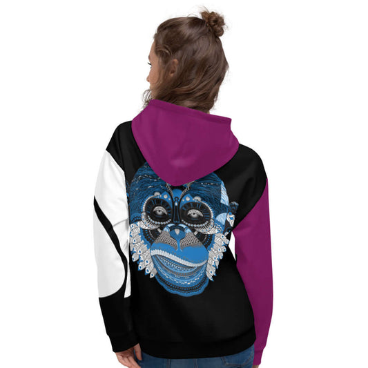 Woman wearing Unisex-Kapuzenpullover N°3 with vibrant monkey print on the back, showcasing cozy and stylish design.
