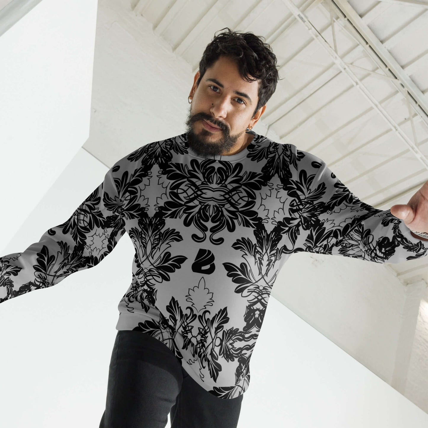 Man wearing Unisex-Pullover N°28 with black intricate design, showcasing handcrafted quality in a bright room.