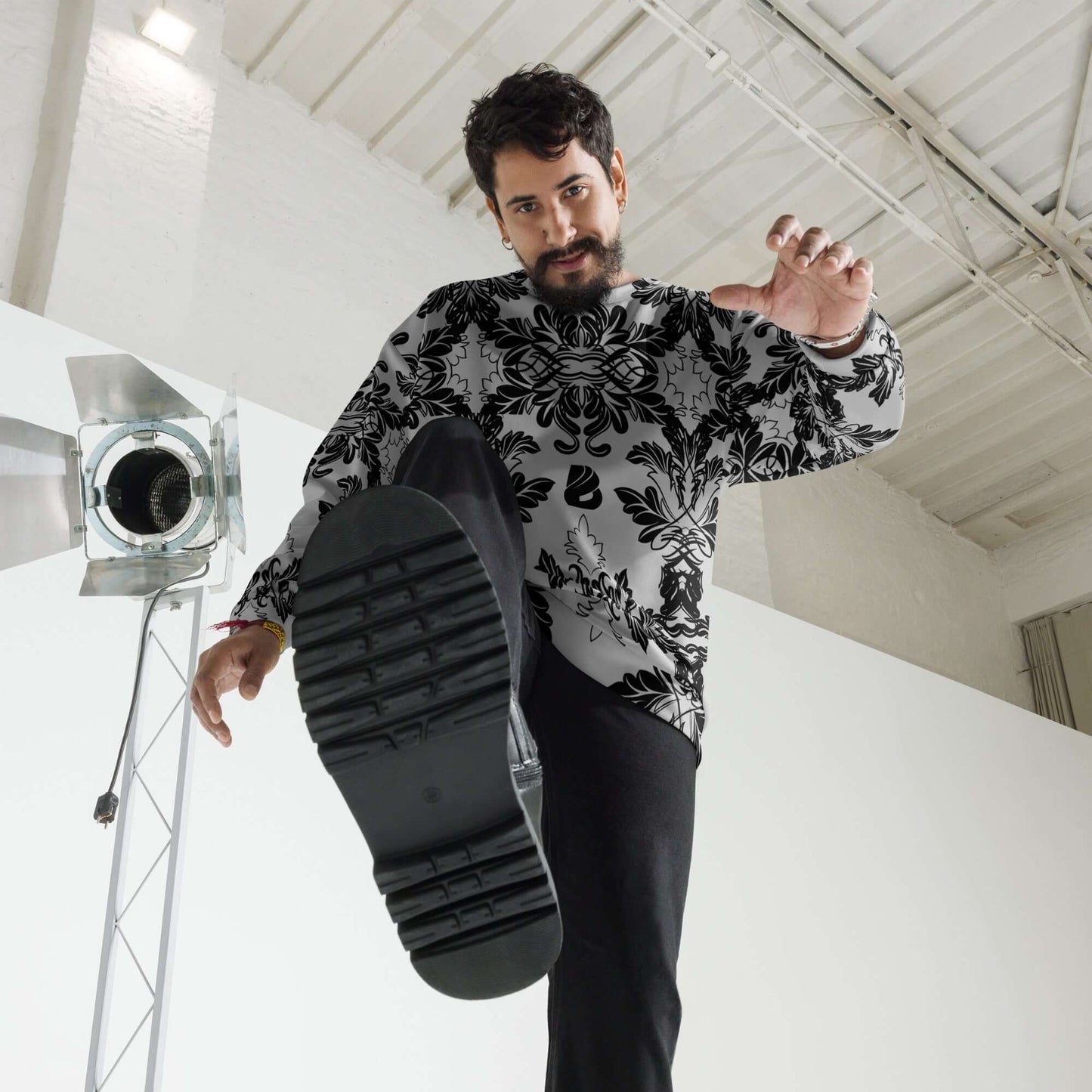 Man wearing Unisex-Pullover N°28, stylishly posing in studio, showcasing intricate black and white design, perfect blend of comfort and fashion.